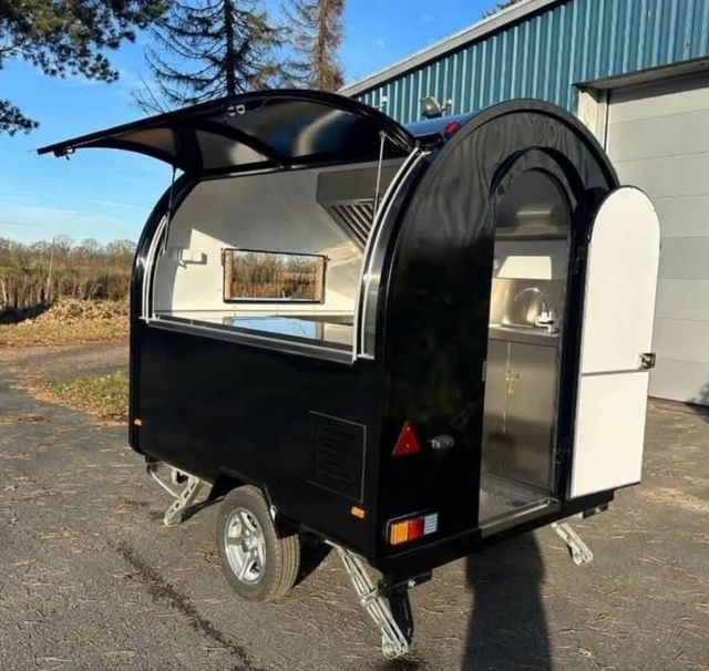 Onbedrukte zwarte foodtrailer met open luik en deur